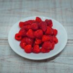 A white plate of strawberries on a wooden table